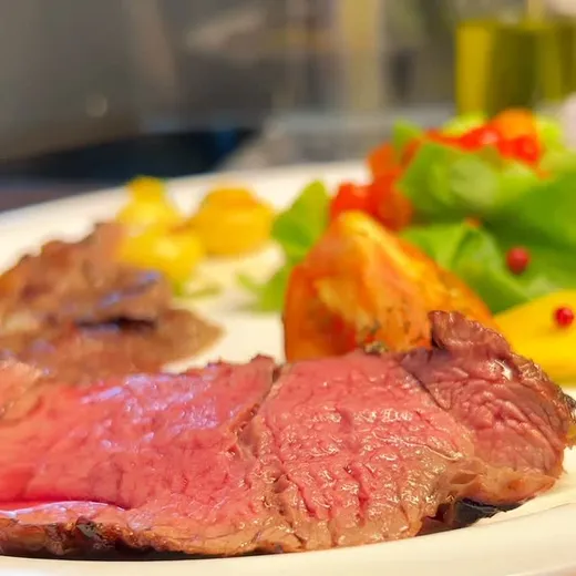 Prato com fatias de carne ao ponto e salada.