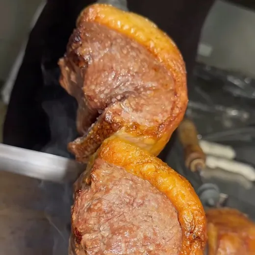Picanha no espeto saindo da brasa.