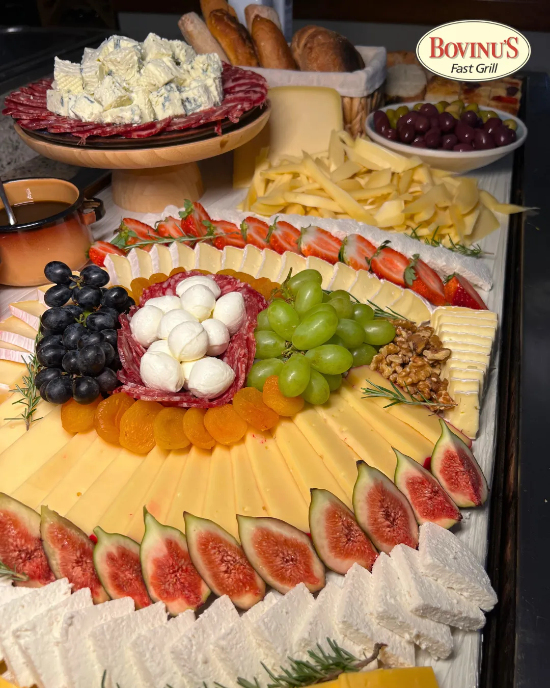 Tábua de frios com queijos, frutas, azeitonas e pães.