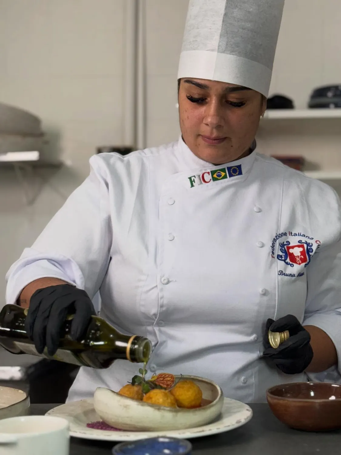 A chef Bruna Marmore finalizando um prato com azeite na cozinha do Mamma Tera.