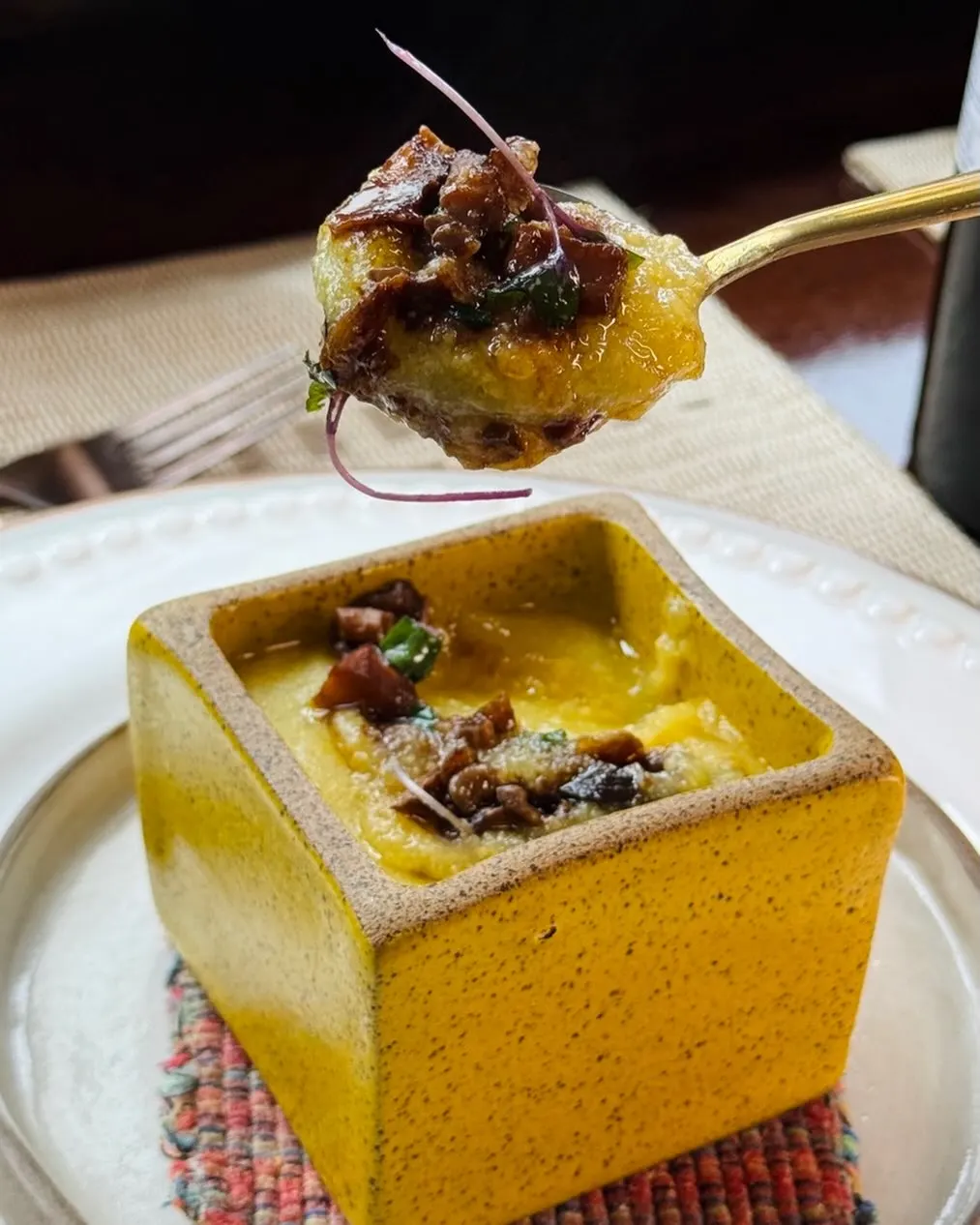 Risoto servido em cumbuca quadrada amarela.
