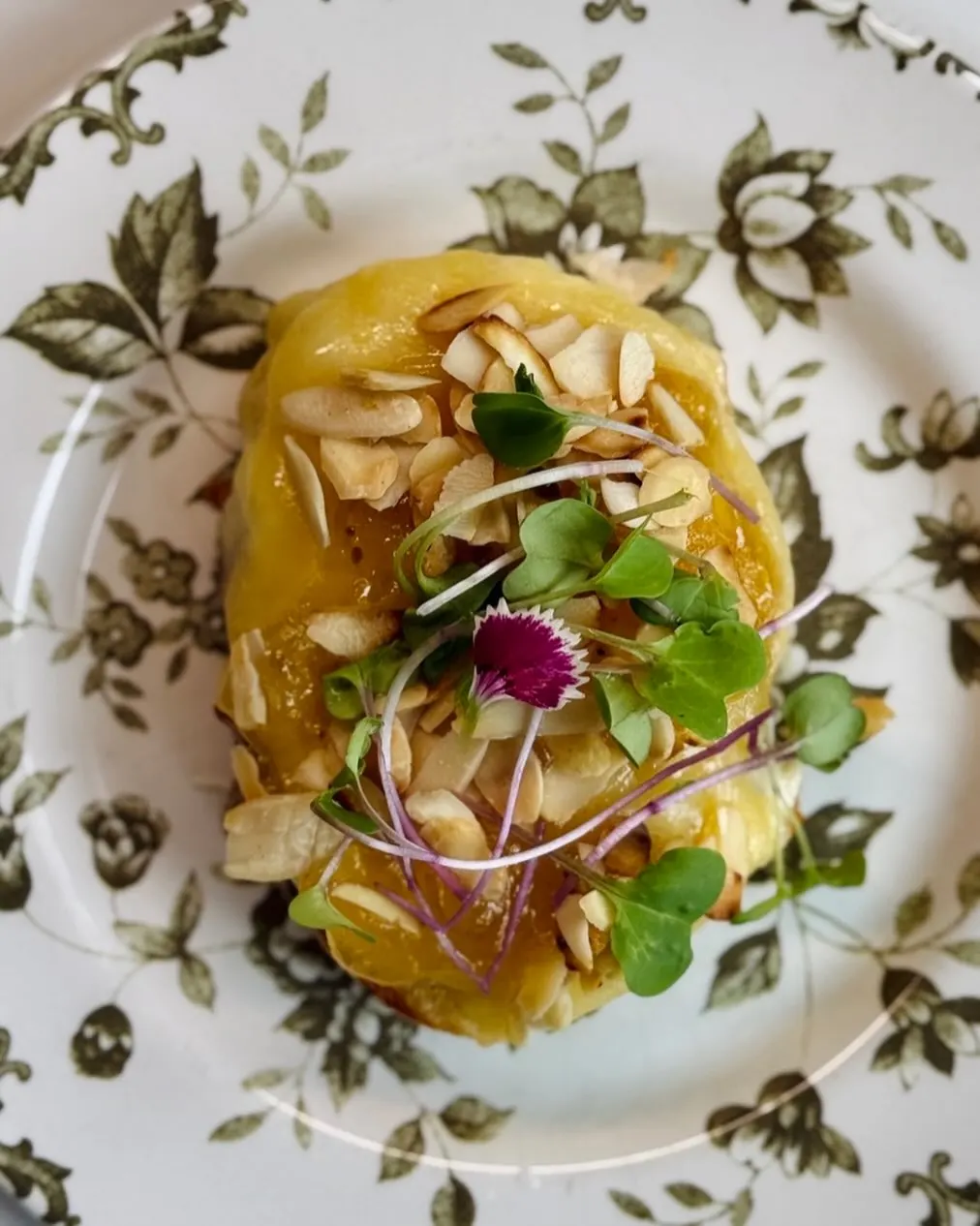 Polenta com amêndoas e brotos em prato florido.